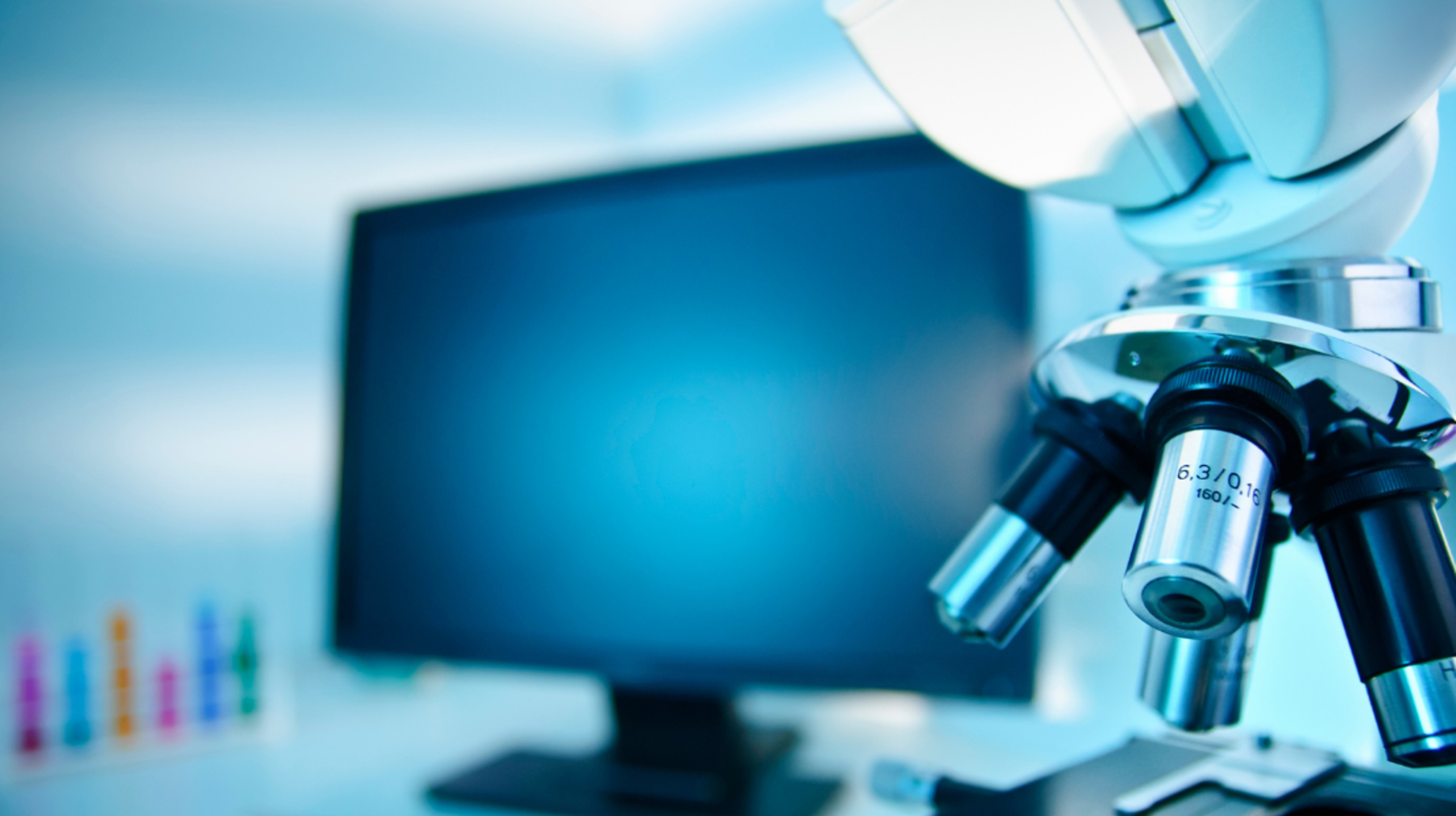 Microscope in front of a screen in a laboratory.