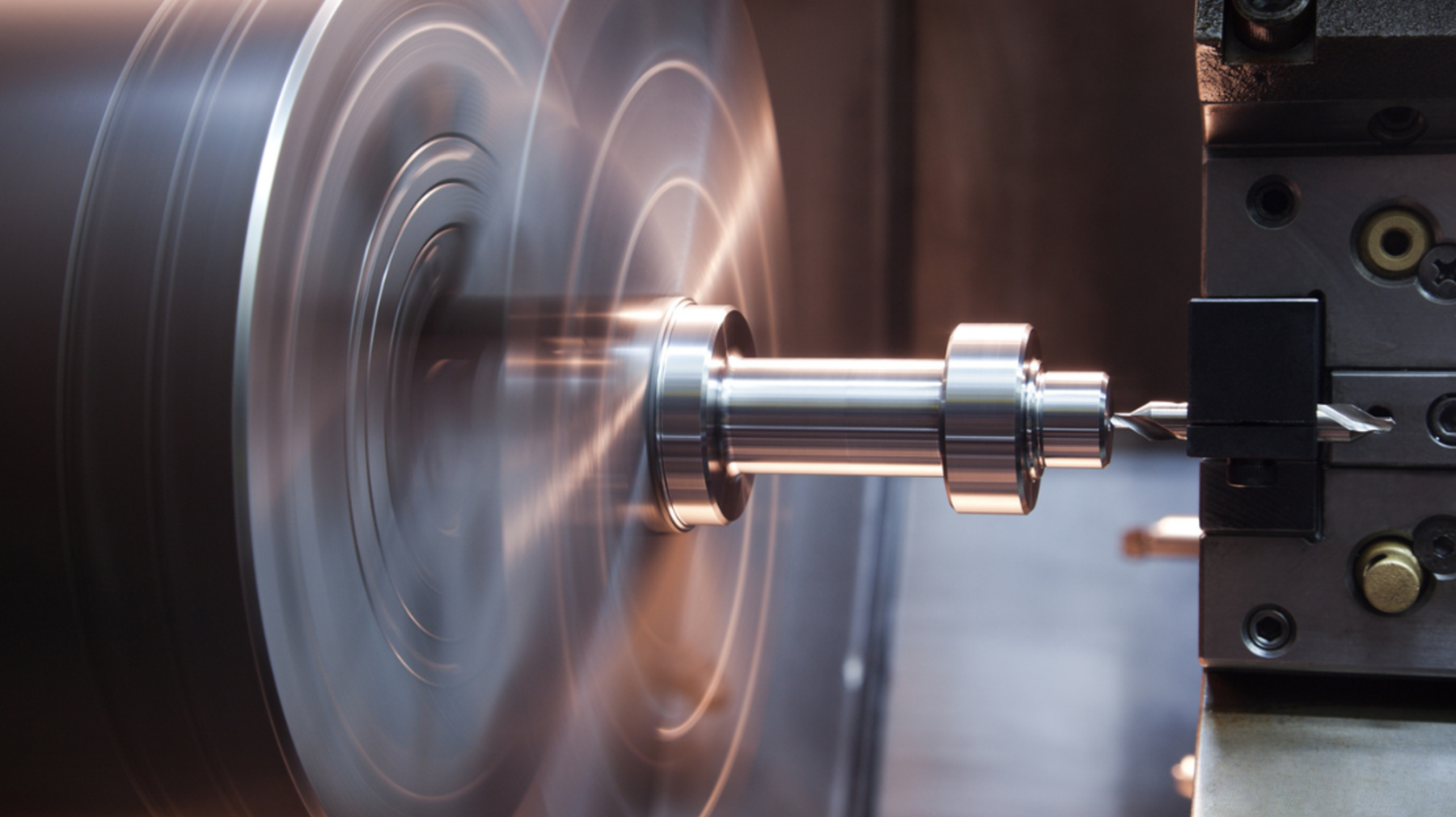 Machining of a cylindrical metal part on an operating CNC lathe.
